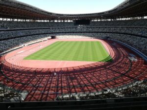 晴天の日に観客席から一望する国立競技場の陸上トラックと緑豊かな天然芝ピッチ